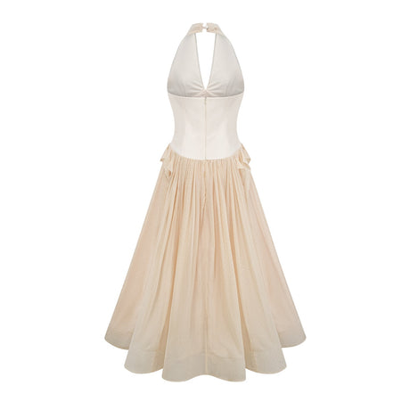 Woman wearing a halterneck tulle midi dress in light color standing against plain background