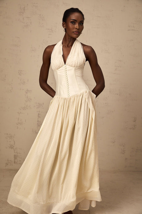 Woman wearing a light colored halterneck tulle midi dress with a fitted bodice and flowy skirt