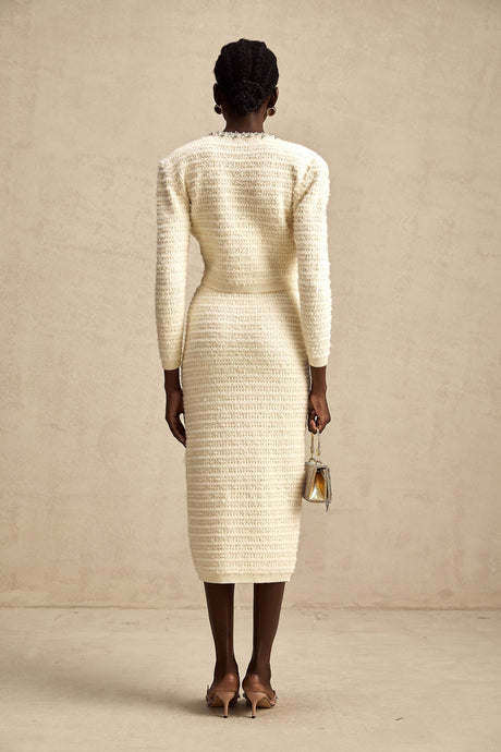 Woman wearing a matching knit cardigan and skirt set with embellishments called Justine The outfit features a coordinated design with decorative details