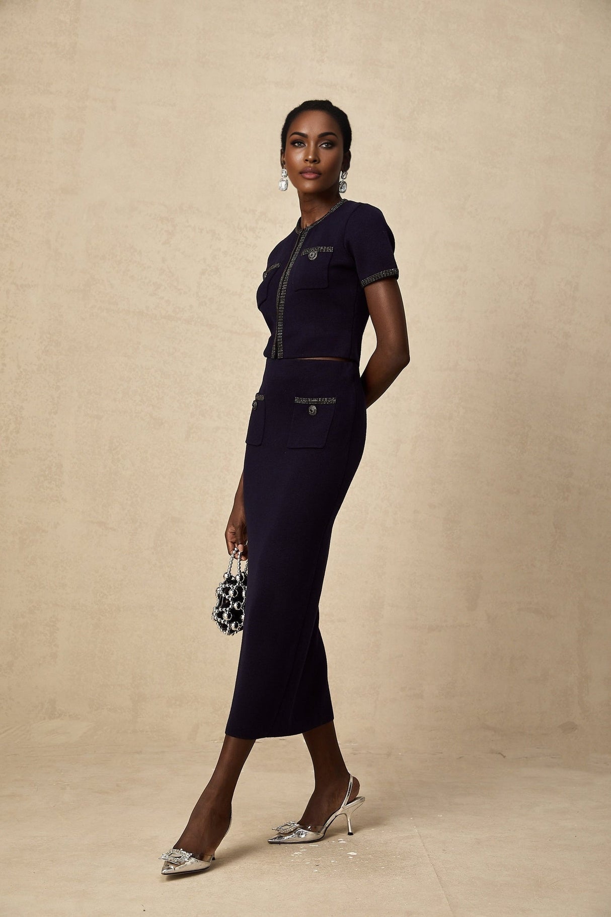 Woman wearing a matching ribbed knit top and skirt set with embellishments in a light color