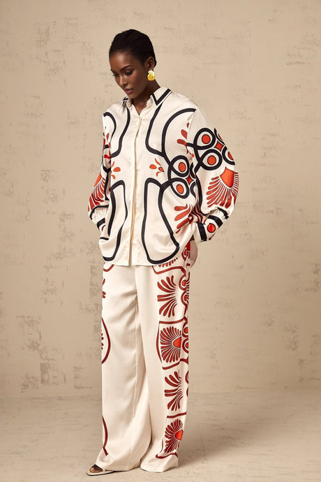Woman wearing a matching set consisting of a shirt and trousers with a colorful graphic print pattern