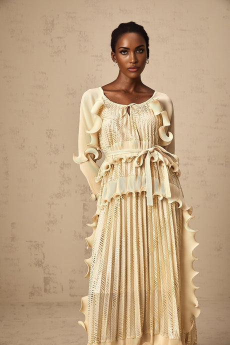Woman wearing a neutral colored midi dress with gilded ruffles and a ruched bodice