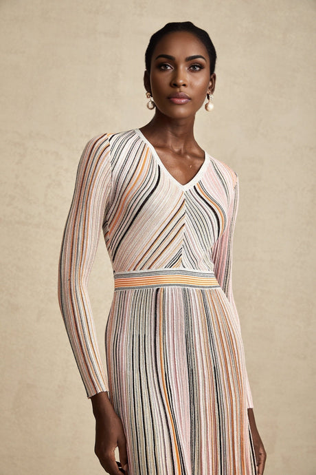 Woman wearing a pink metallic pleated midi dress with a flowy skirt and fitted bodice standing against a plain background