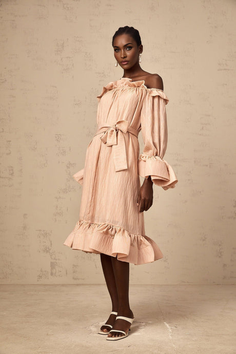 Woman wearing a pink midi dress with tied waist and ruffled details
