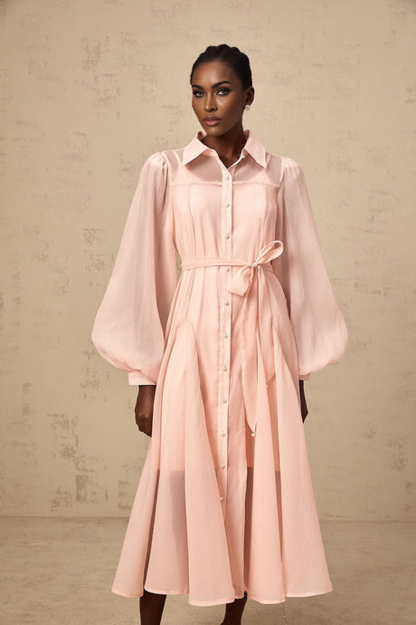 Woman wearing a pink midi length shirt dress with a tied waist detail and collar
