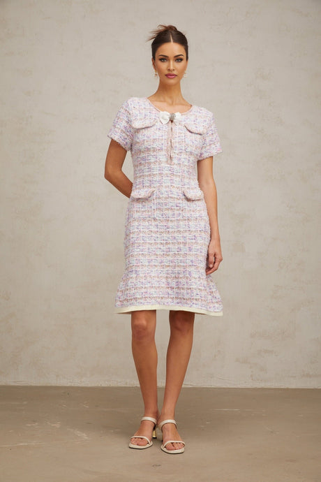 Woman wearing a purple and white checked knit midi dress with long sleeves standing against a plain background