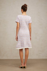 Woman wearing a purple checked knit midi dress with long sleeves and a fitted silhouette standing against a plain background