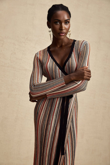 Woman wearing a striped metallic midi dress with wrap design featuring a belted waist and long sleeves