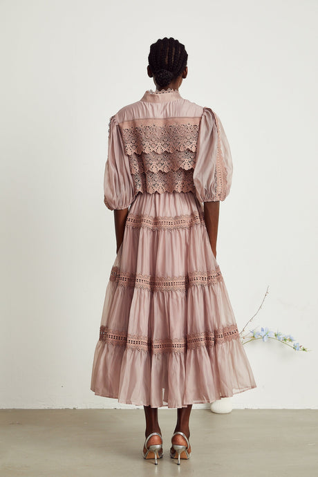 Woman wearing a white lace midi dress with cutout details and tiered skirt