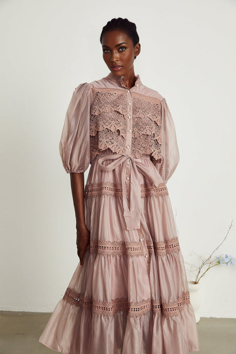 Woman wearing a white lace midi dress with tiered skirt and cut out details