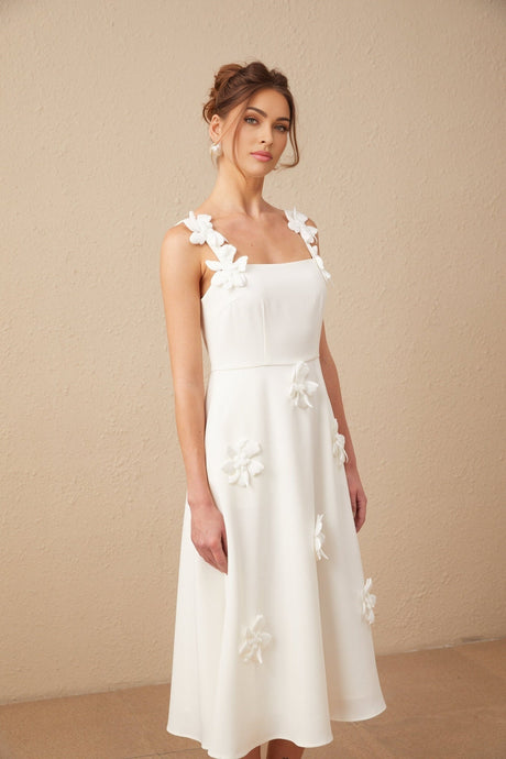 Woman wearing a white midi dress with faux flower details and a square neckline