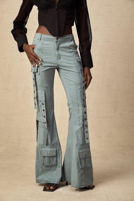 Woman wearing beige flared cargo trousers with belt loops and multiple pockets standing in casual pose