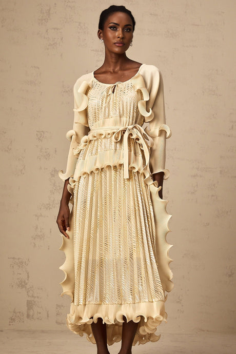 Woman wearing beige ruffled midi dress with gilded details standing in neutral pose