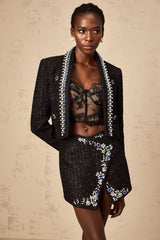 Woman wearing black tweed jacket and matching skirt set with crystal embellishments elegant formal outfit