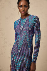 Woman wearing blue and white zigzag patterned knitted midi dress with long sleeves and fitted silhouette