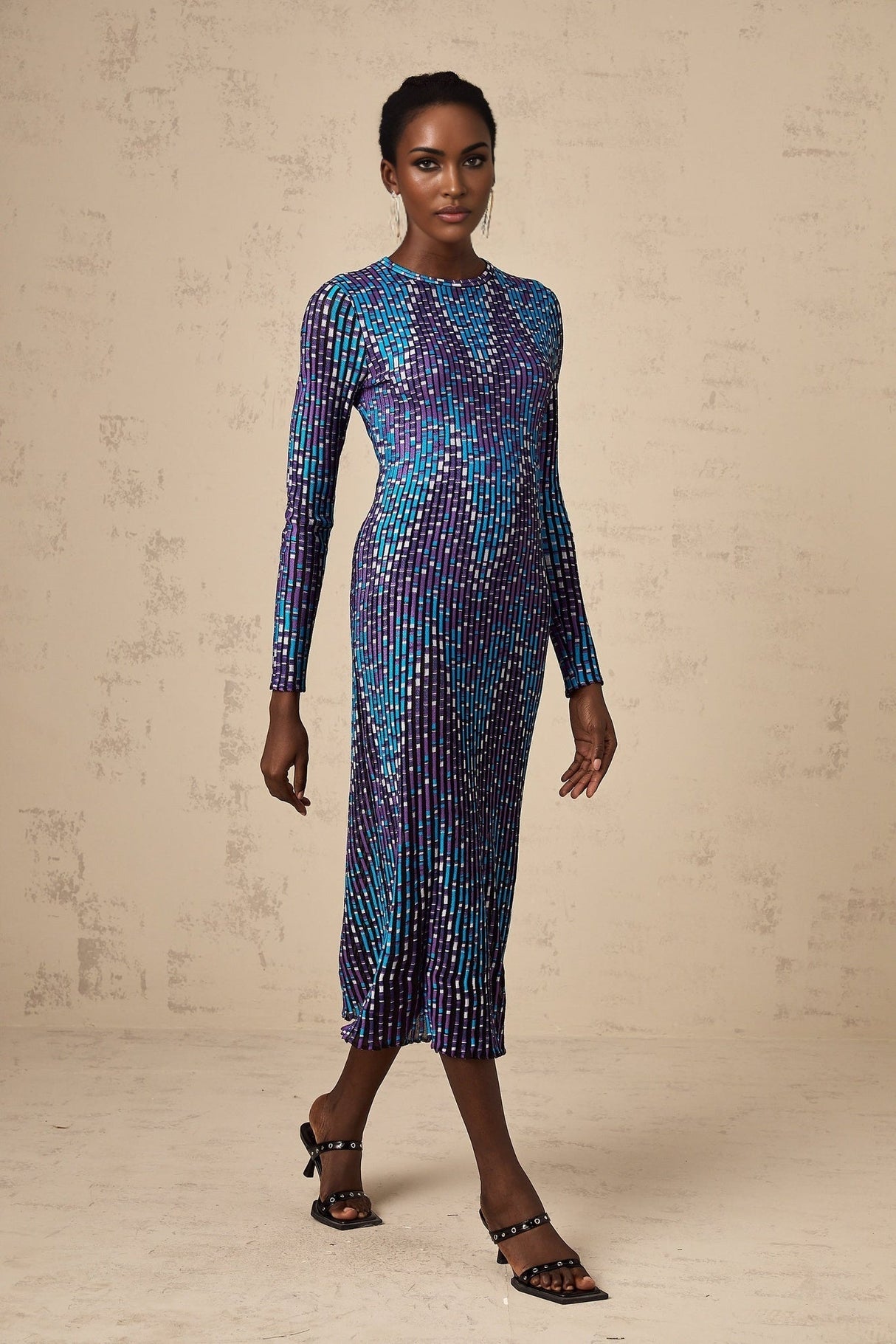 Woman wearing blue and white zigzag patterned knitted midi dress with long sleeves and round neckline