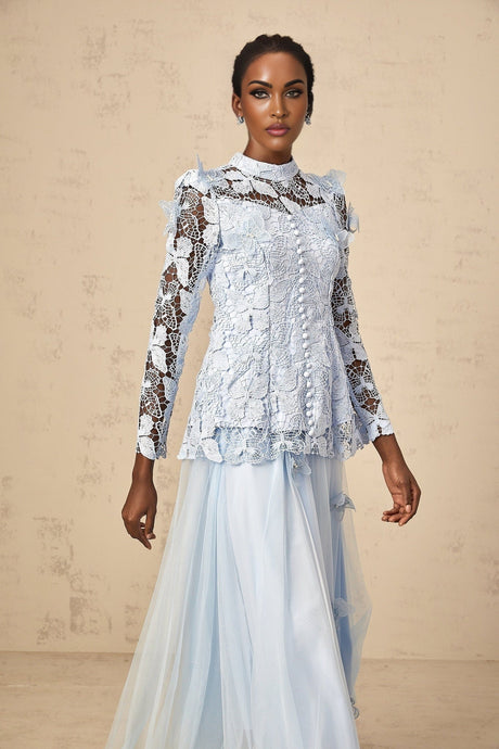 Woman wearing blue sequined lace matching set with sleeveless top and short skirt shimmering fabric against light background