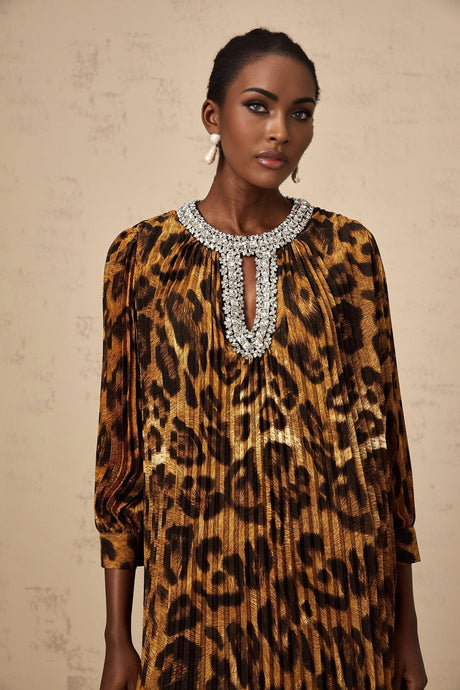 Woman wearing brown leopard print midi dress with embellishments and long sleeves standing against plain background