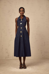 Woman wearing dark blue denim midi dress with cutout details standing against plain background