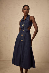 Woman wearing dark blue denim midi dress with cutout details standing against plain background