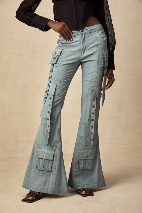 Woman wearing green flared cargo trousers with belt loops and multiple pockets standing in casual pose