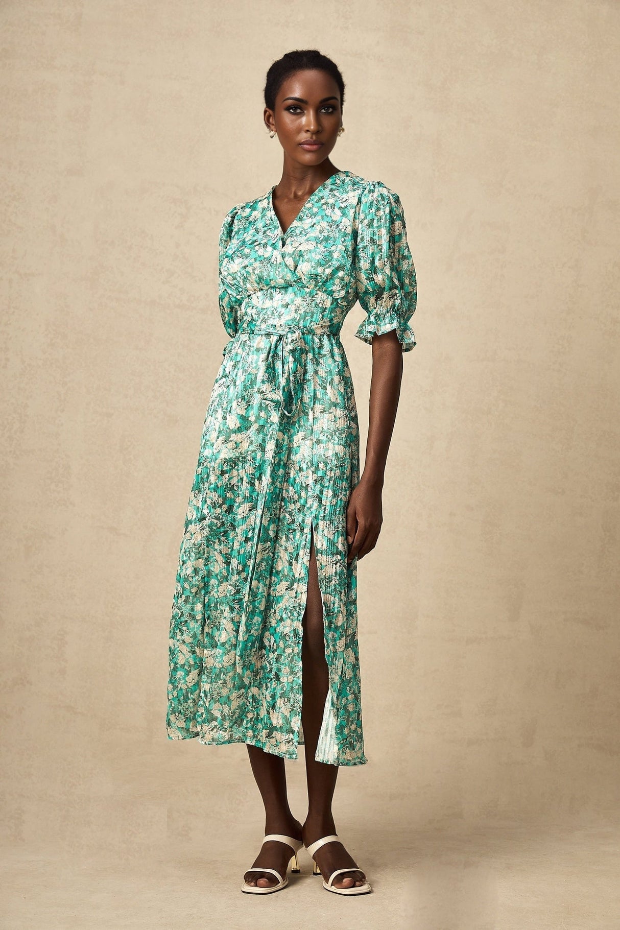 Woman wearing green midi dress with floral print and high slit standing in casual pose