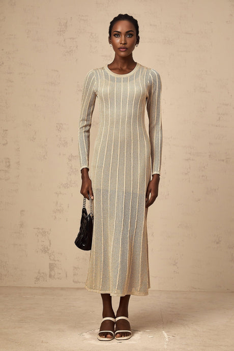 Woman wearing khaki colored fitted knit midi dress with long sleeves and ribbed texture standing against plain background