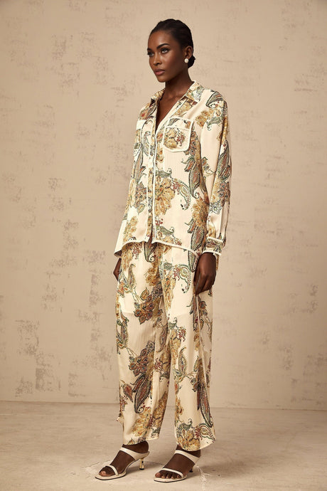 Woman wearing matching floral print shirt and trousers in neutral tones standing casually