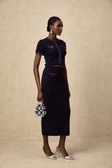 Woman wearing matching ribbed knit top and skirt set in light color with embellished details