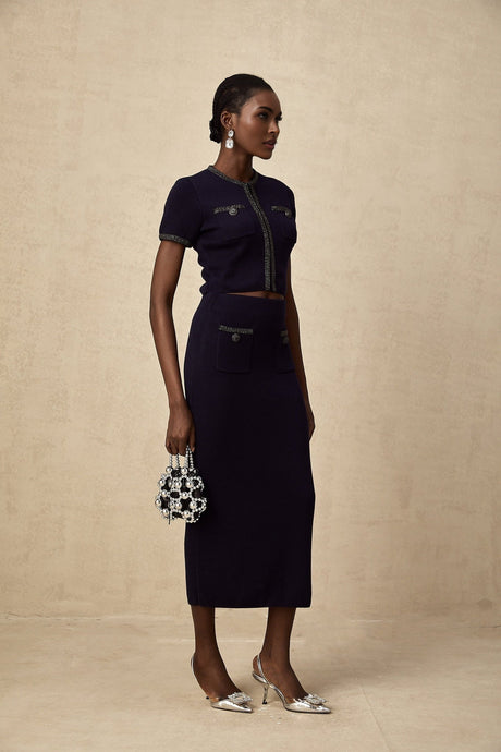 Woman wearing matching ribbed knit top and skirt set in light color with embellished details