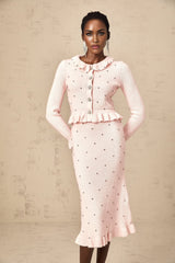 Woman wearing pink argyle patterned knit cardigan and matching skirt set