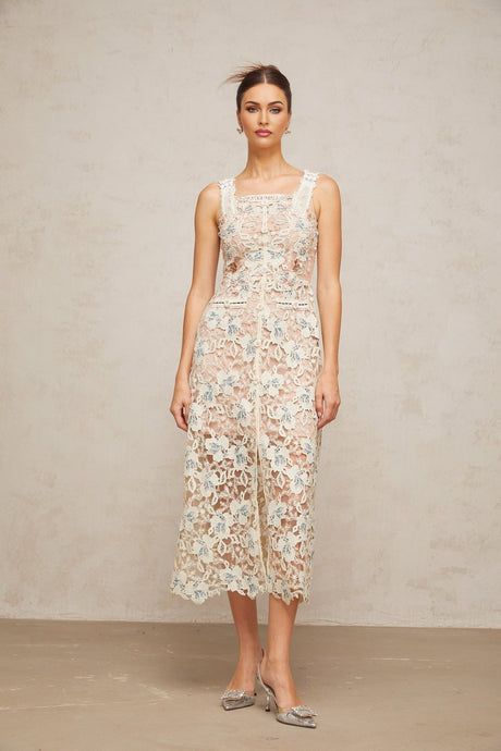 Woman wearing white Aline midi dress with floral lace pattern and short sleeves standing against plain background