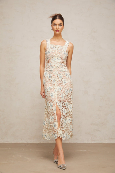 Woman wearing white Aline midi dress with floral lace pattern standing in neutral background