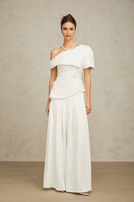 Woman wearing white creased top and matching trousers standing in relaxed pose