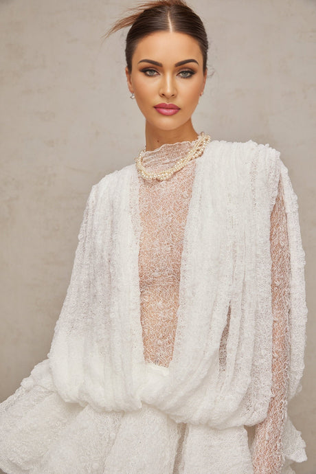 Woman wearing white lace matching set including top shorts and dress semi sheer fabric visible lace details on all pieces