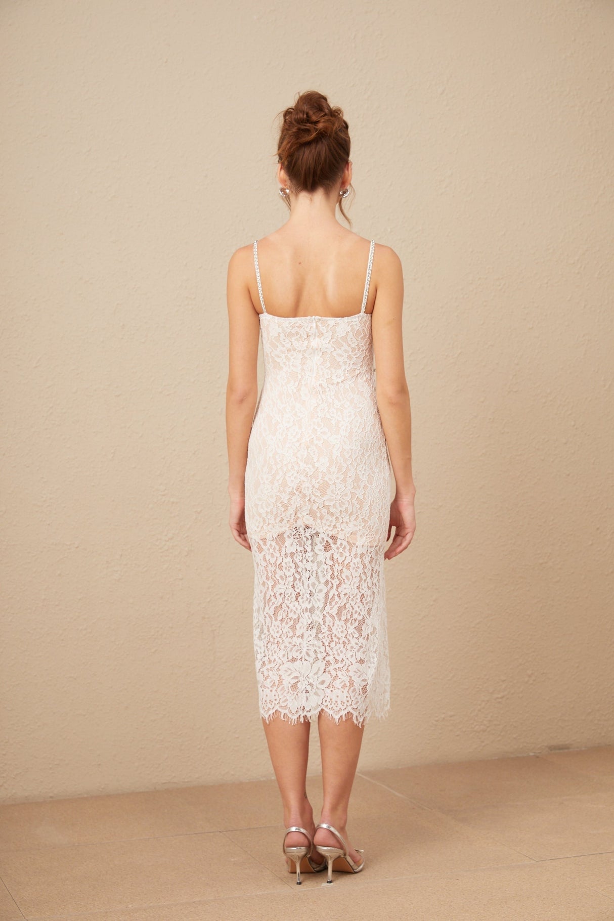 Woman wearing white lace midi dress with crystal embellished bustier top and fitted silhouette