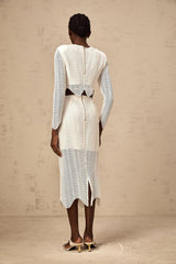 Woman wearing white matching set with wavy woven texture top and skirt standing against plain background