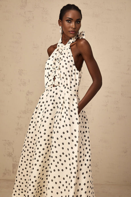 Woman wearing white midi dress with polka dots and bow detail at waist
