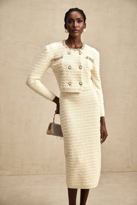 Young woman wearing a matching knit cardigan and skirt set with embellishments and sparkly details in a light color