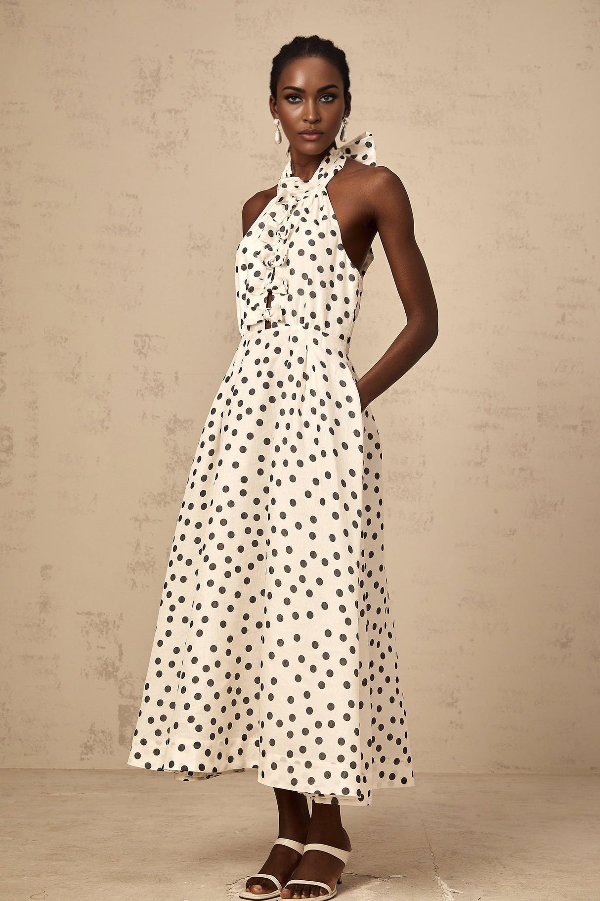 Young woman wearing a white midi dress with black polka dots and a bow detail at the neckline