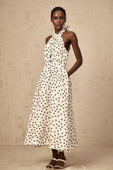 Young woman wearing a white midi dress with black polka dots and a bow detail at the neckline